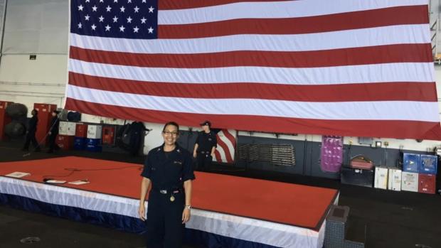 Jessica Espinoza in her uniform in front of a large American flag.