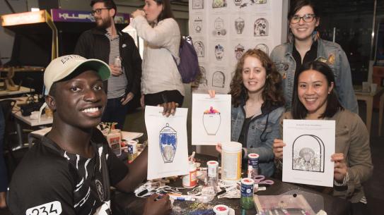 group of students holding up drawings at IDM showcase