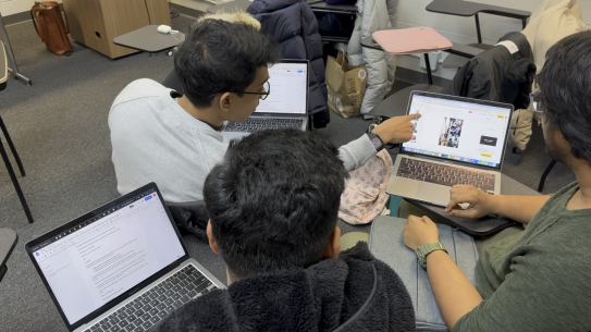 NYU students discussing in groups while using laptops