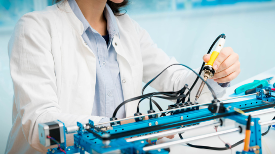 female student in lab coat working with microcontroller and robot cnc module