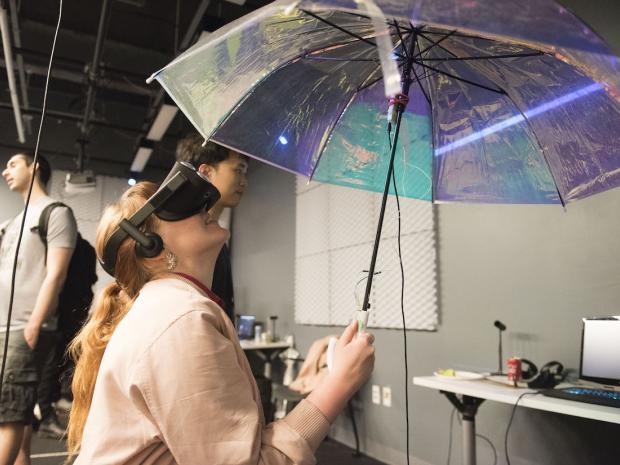 student wearing VR headset looking up at umbrella
