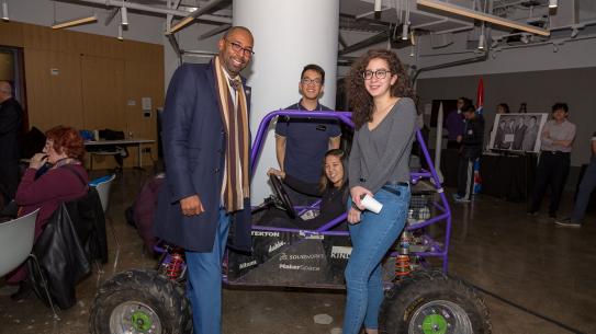 Students in NYU Tandon's Motorsports team display their vehicle to an alumnus