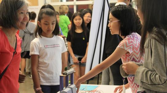 students discuss their expo project with a parent 