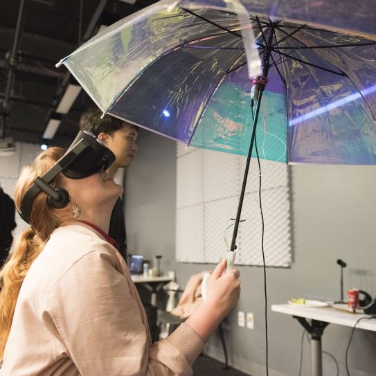 student wearing VR headset looking up at umbrella