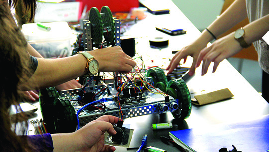 student hands working on robot